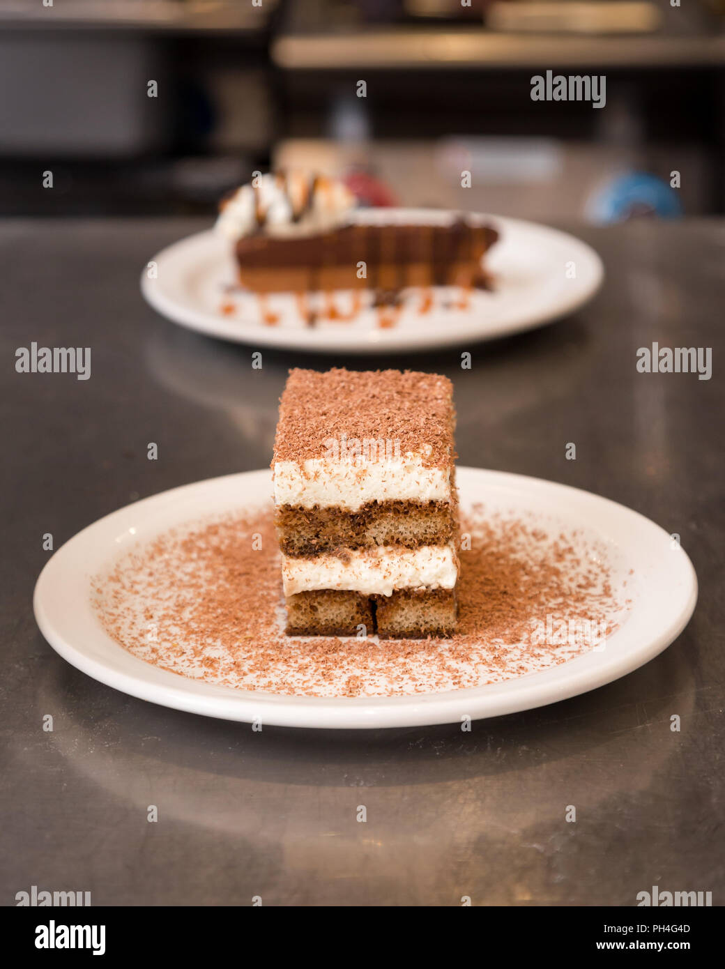 Tiramisu dusted with chocolate with a chocolate tart in the background. Stock Photo