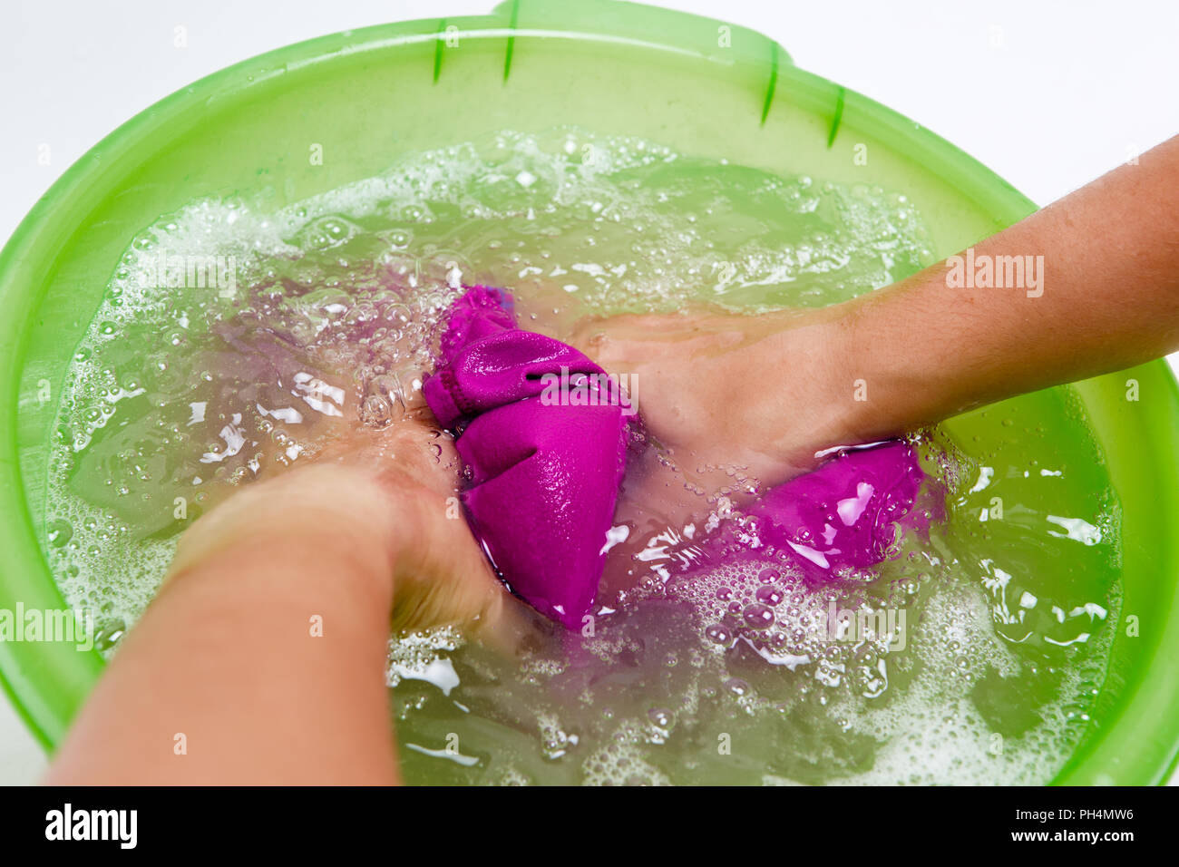 Photo on top of girl hands washing violet clothes in green basin Stock Photo