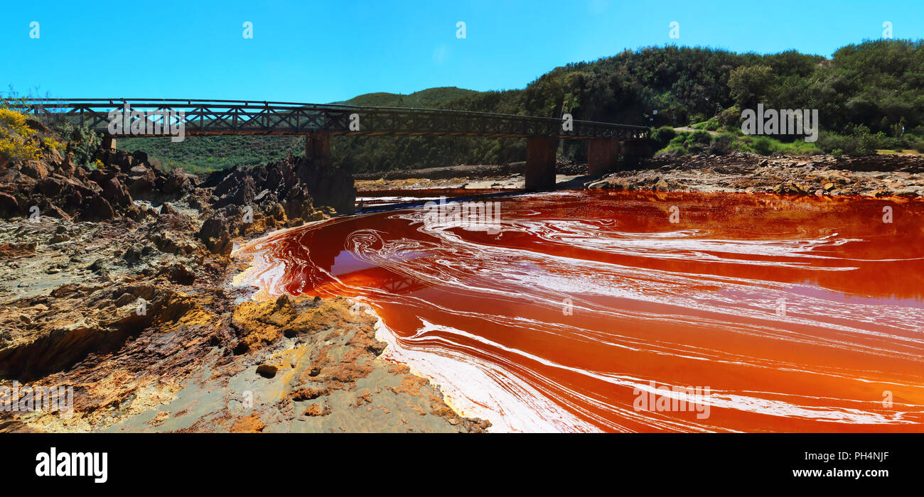 The rare color of the waters of the Odiel river and the abstract forms that form its foam, next to an iron bridge, in the province of Huelva, Spain Stock Photo