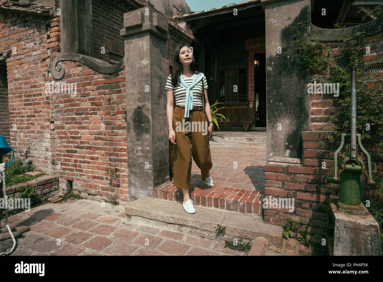 asian tourist visiting the old traditional house. looking upward in the door. Stock Photo