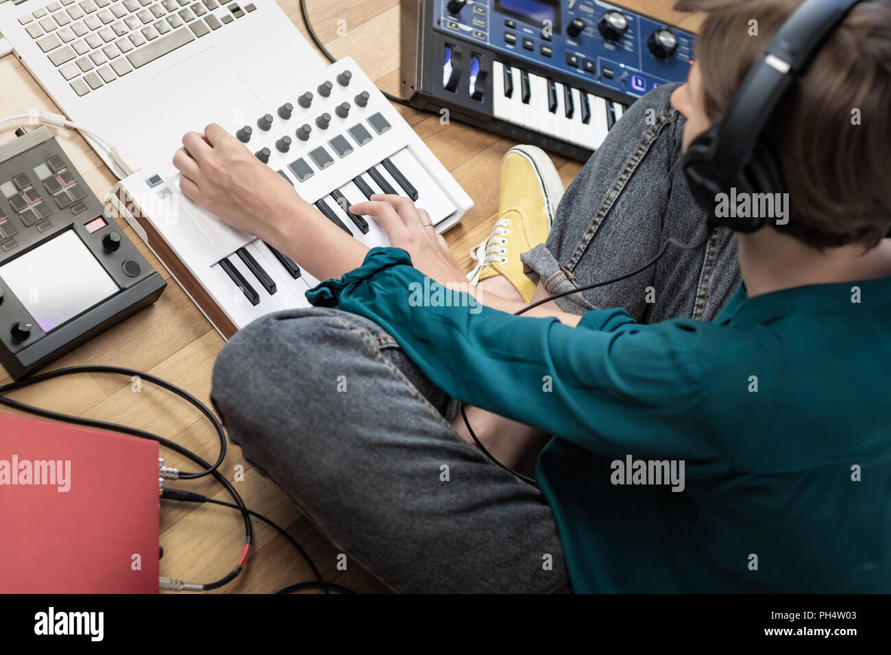Young woman wearing studio headphones producing modern electronic music.  Female musician at home studio with instruments, laptop and effects  processo Stock Photo - Alamy