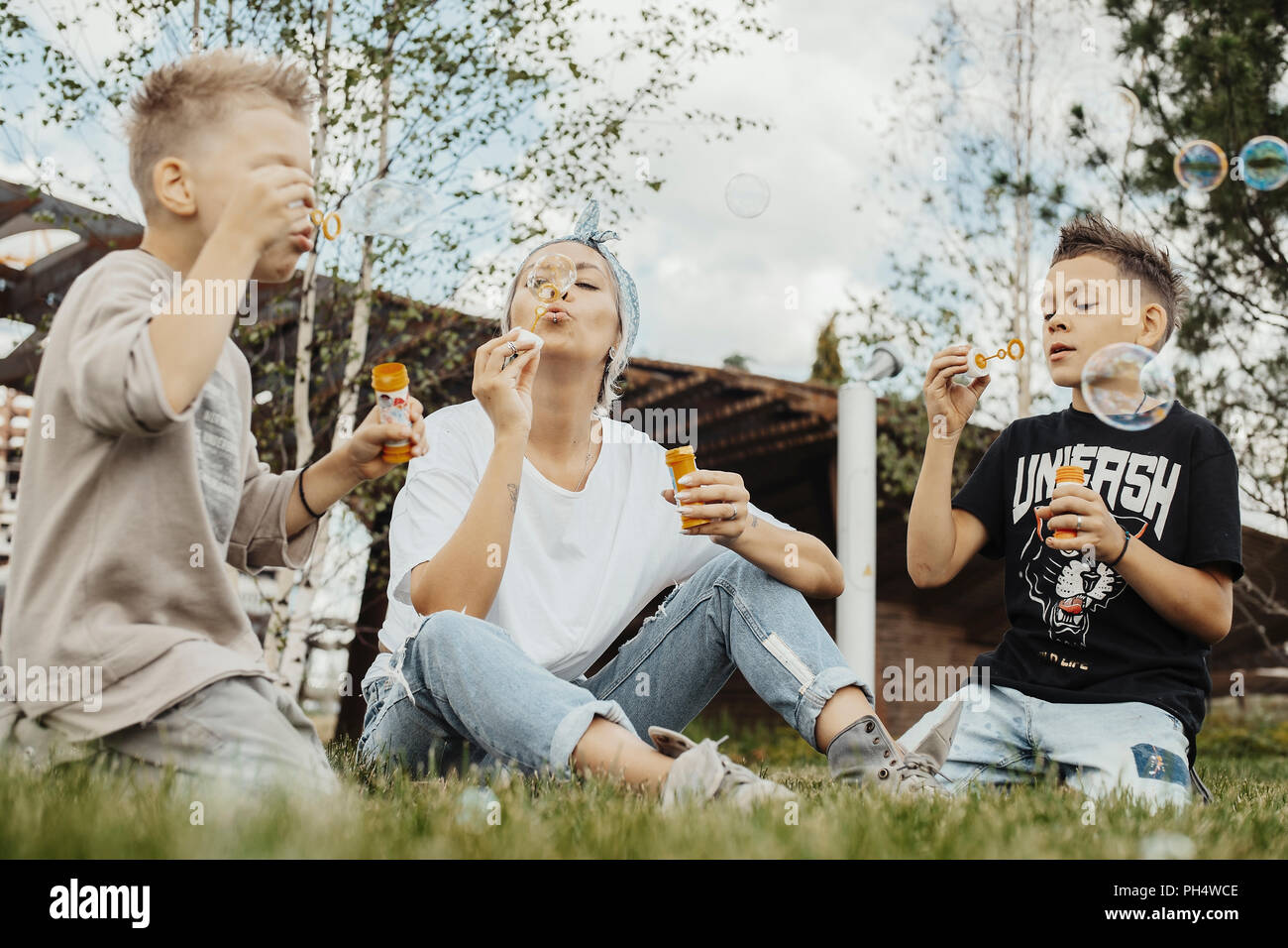 Close up of family blowing bubbles outdoors in the park. Stock Photo