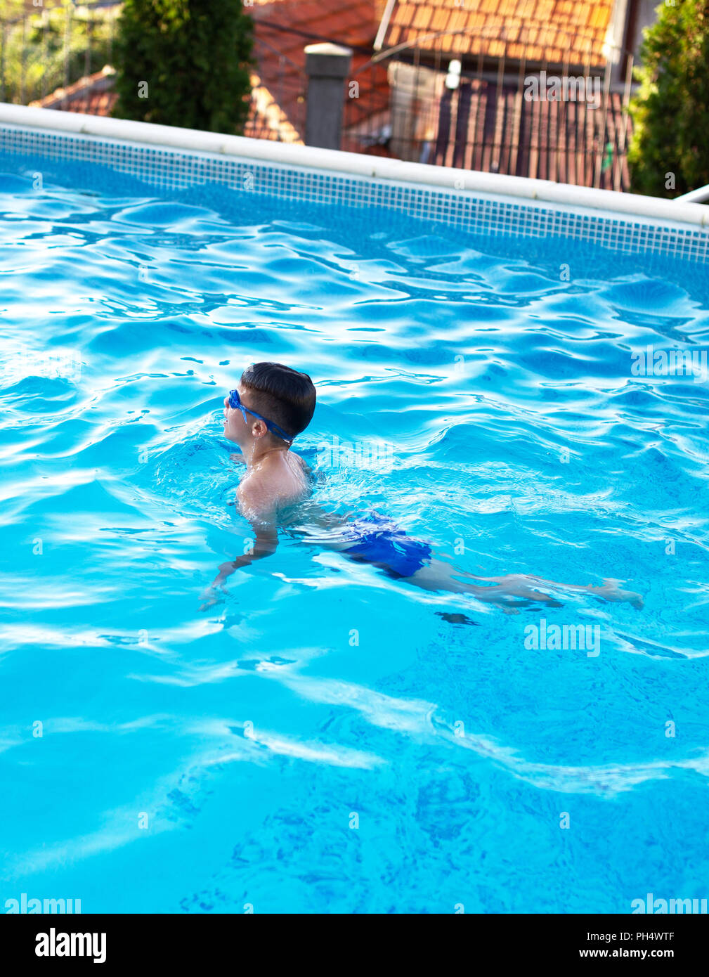 Little boy in goggles swim breaststroke in swimming pool Stock Photo