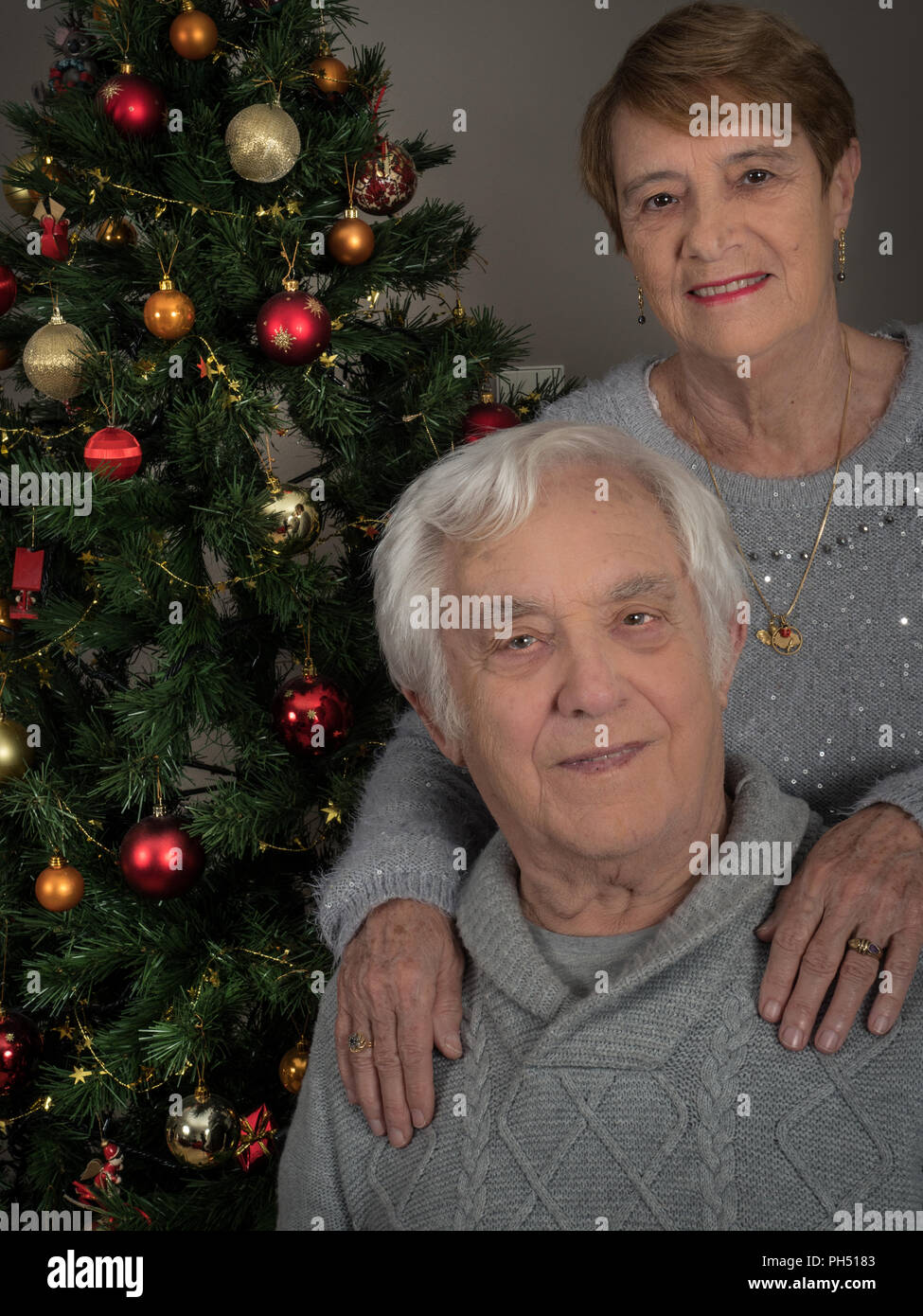 Horizontal portrait of an elderly couple by a Christmas tree Stock Photo
