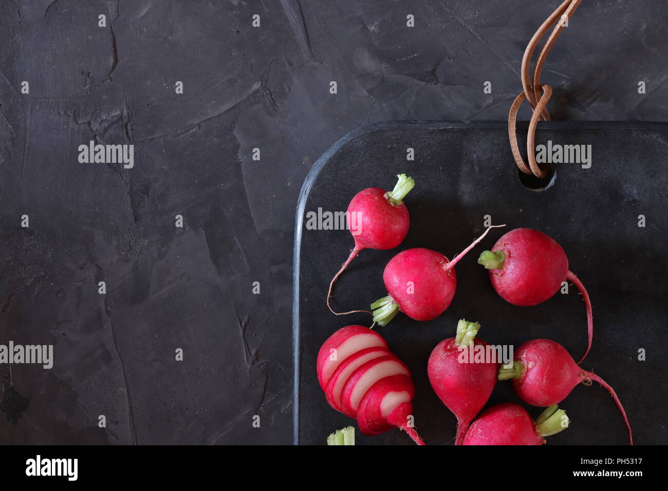 Red radishes on dark surface, flat lay, space for copy Stock Photo