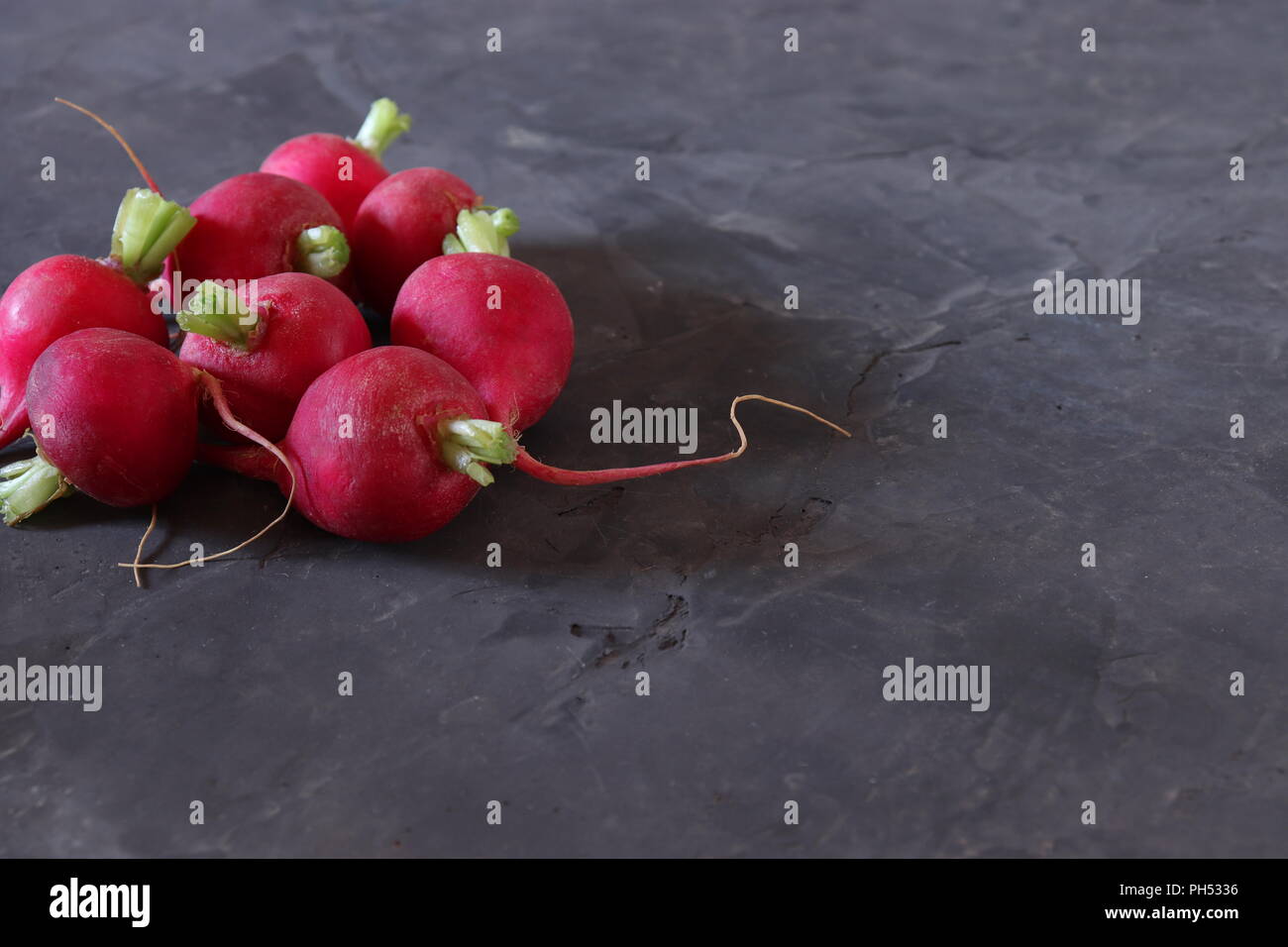 Red radishes on dark grey surface, with space for copy Stock Photo