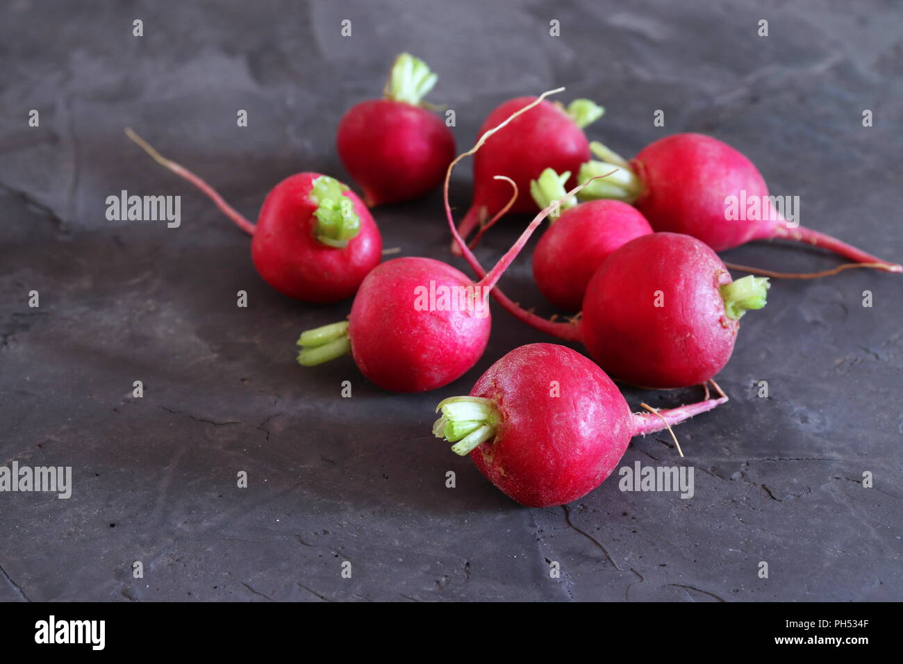Red radishes on dark grey surface, with space for copy Stock Photo