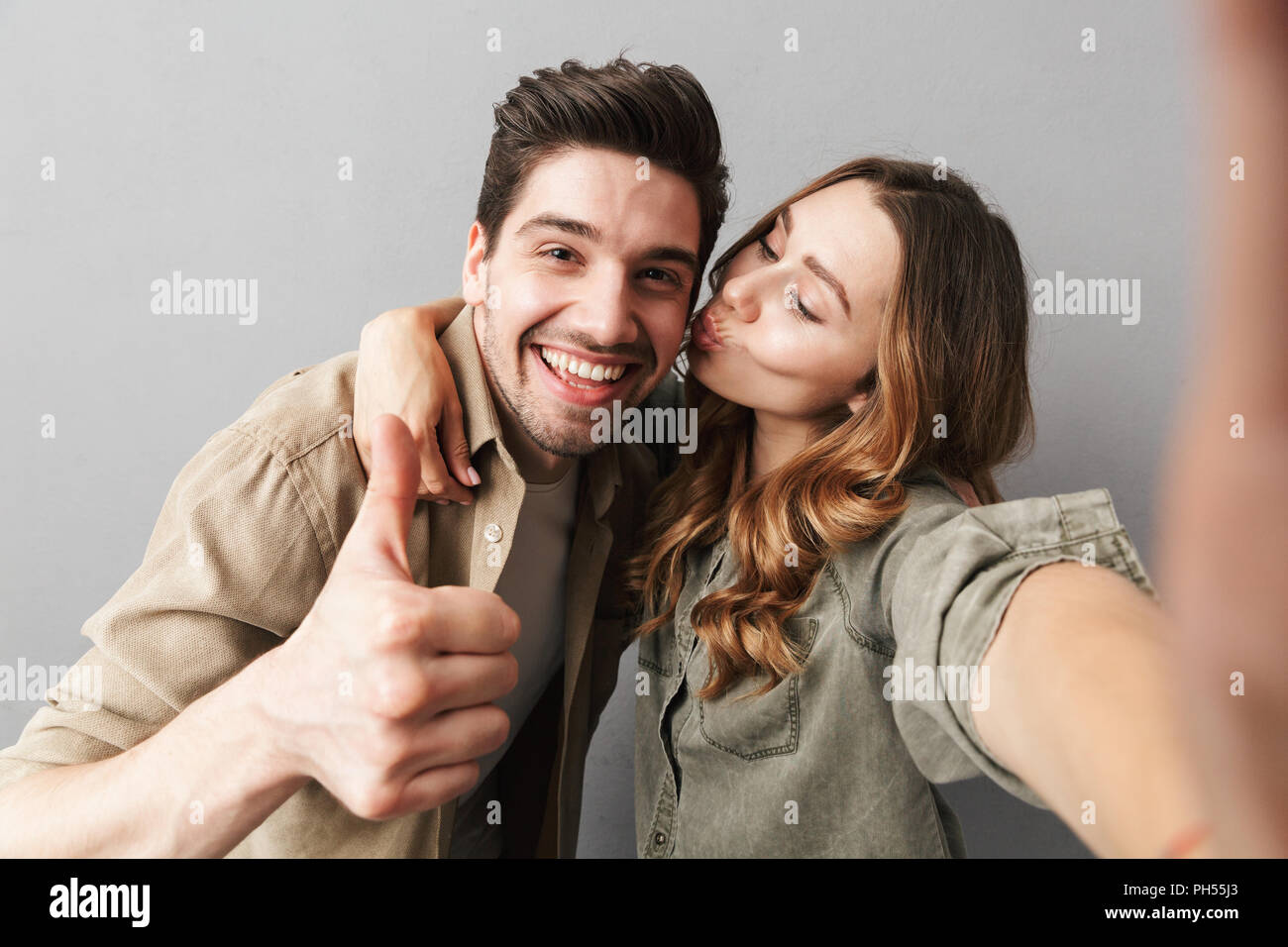 Portrait of a happy young couple hugging while taking a selfie and ...