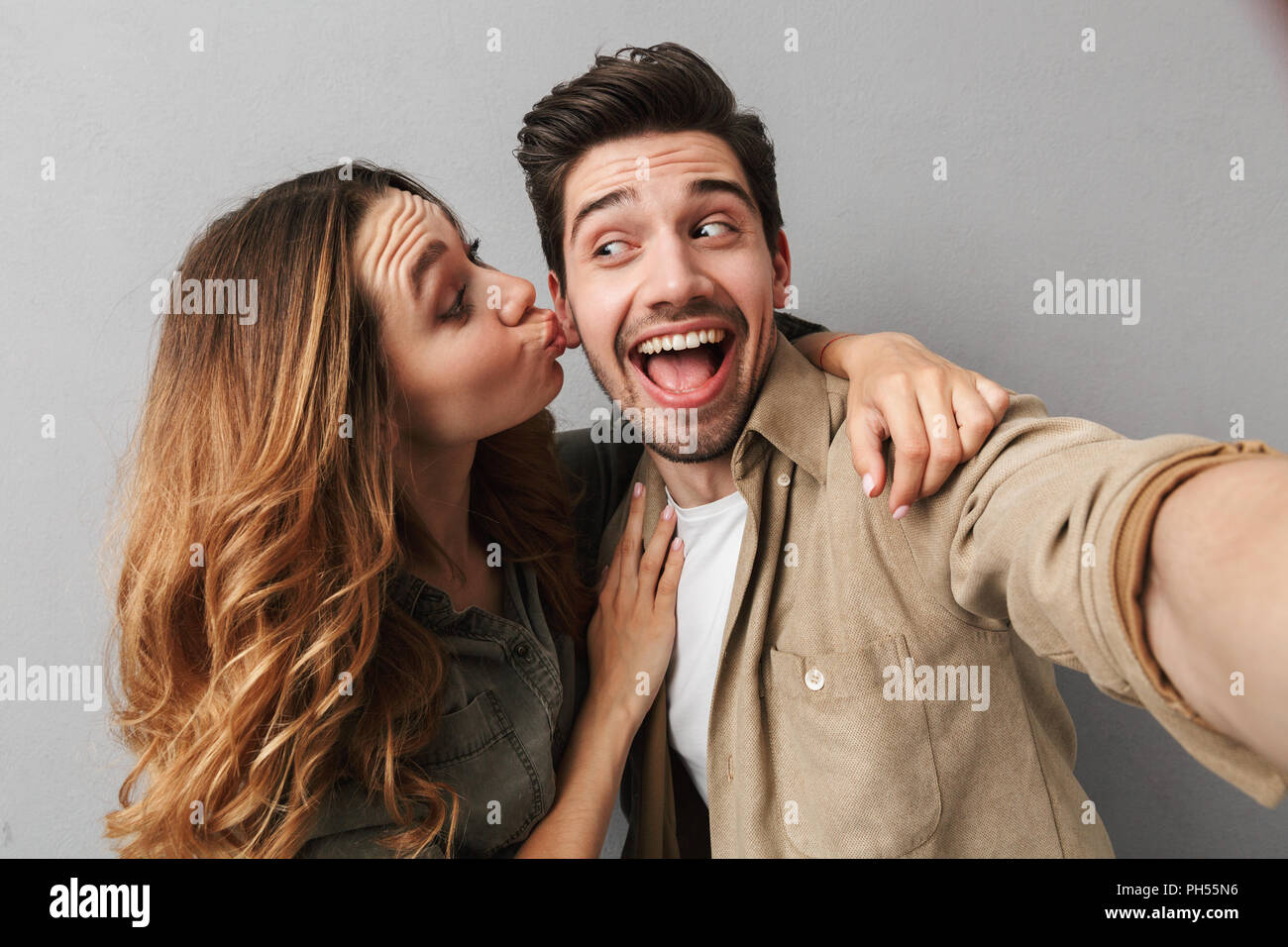 Portrait of a happy young couple hugging while taking a selfie and ...