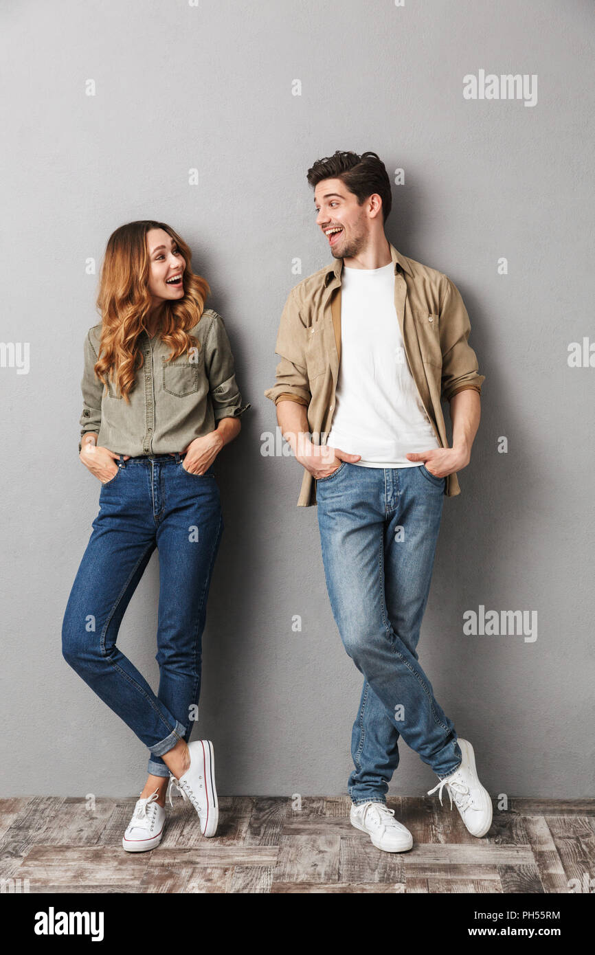 Full length portrait of a smiling young couple standing together ...