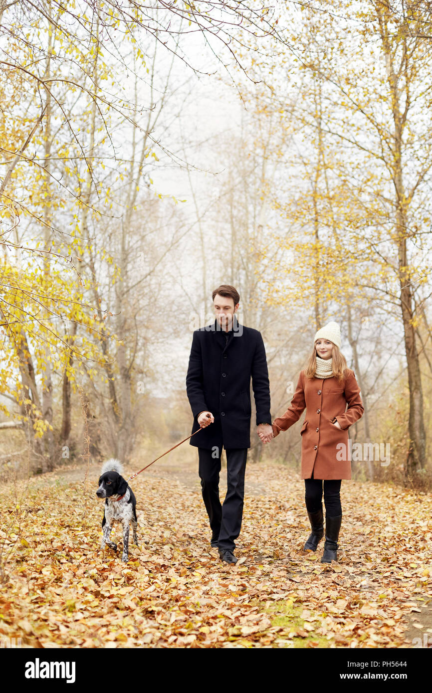 Couple walking with dog in the Park and hugging. Autumn walk men and ...