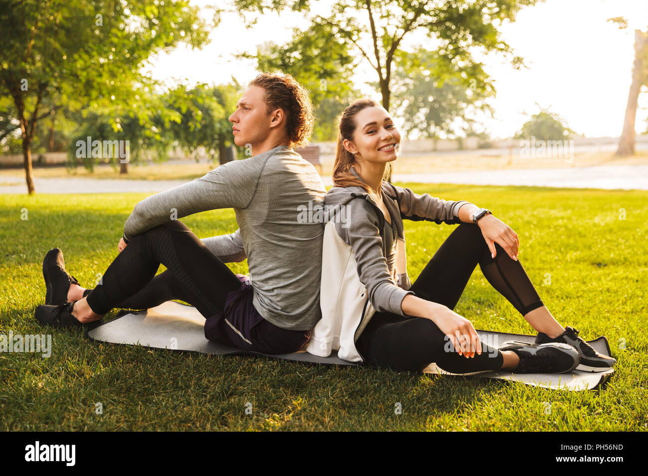 Image of happy sporty people man and woman 20s in tracksuits sitting on ...