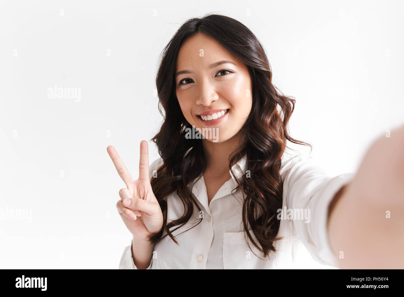 Portrait of optimistic chinese woman with long dark hair smiling and taking  selfie photo with peace sign isolated over white background in studio Stock  Photo - Alamy