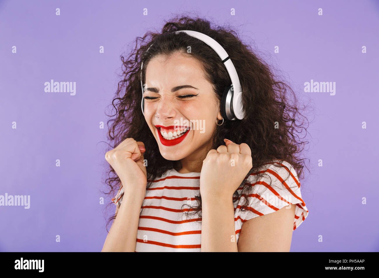 Portrait of a cheerful young casual woman listening to music with ...