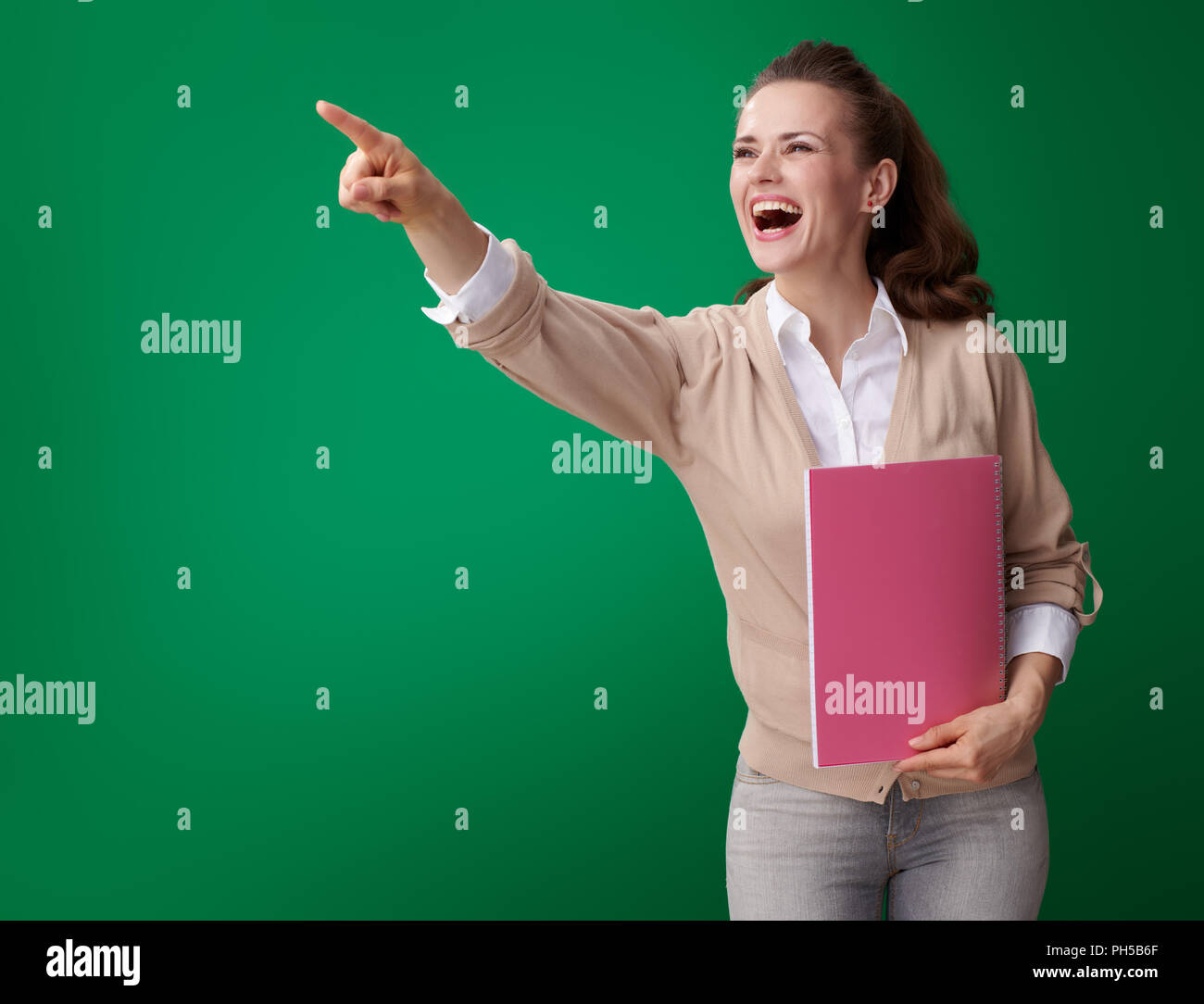 happy young student woman with pink notebook pointing at something ...
