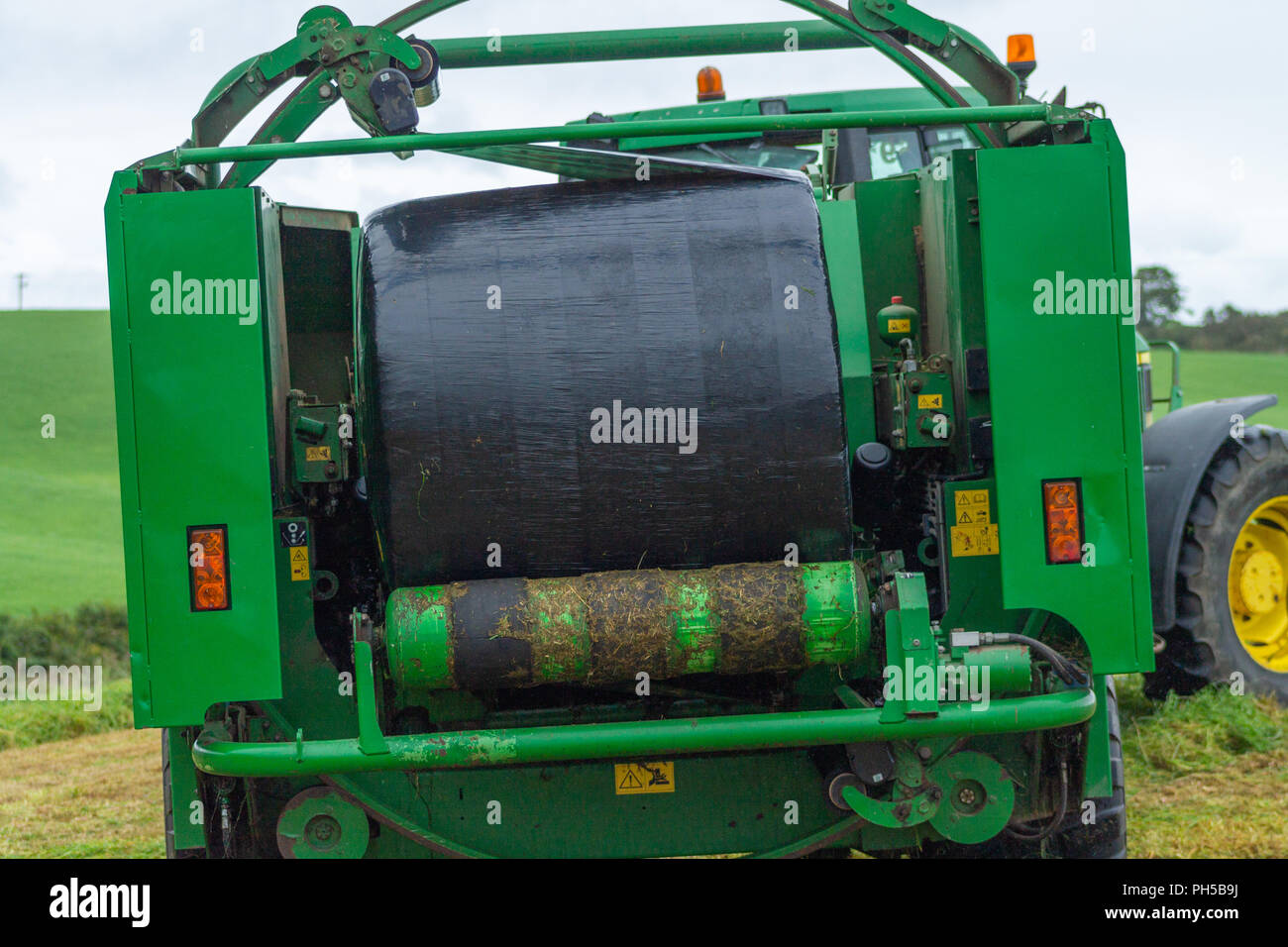 McHale baler baling silage in black plastic sheet on a farm in ireland Stock Photo