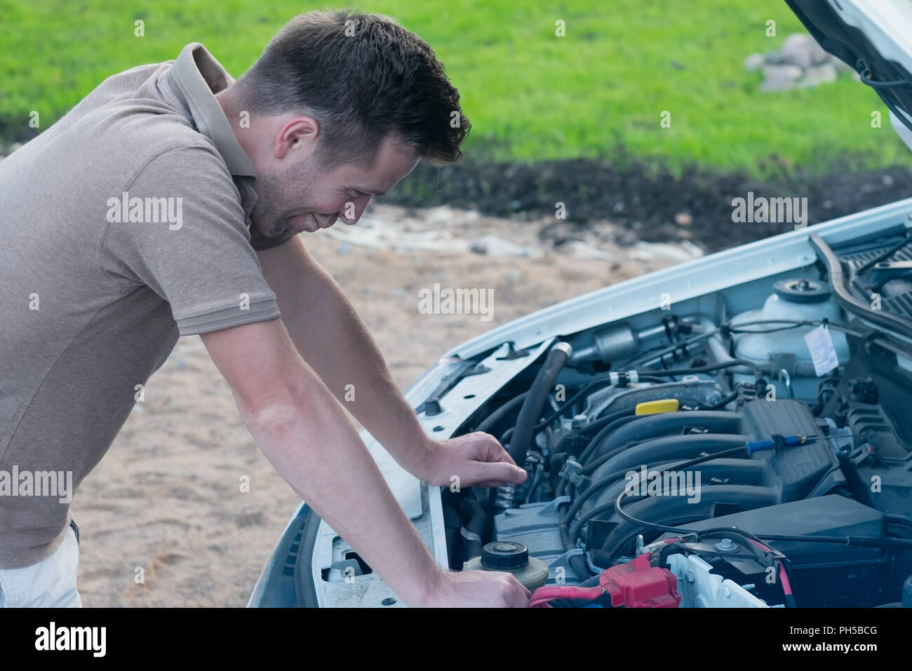 young stressed man having trouble with his broken car looking in frustration at failed engine Stock Photo