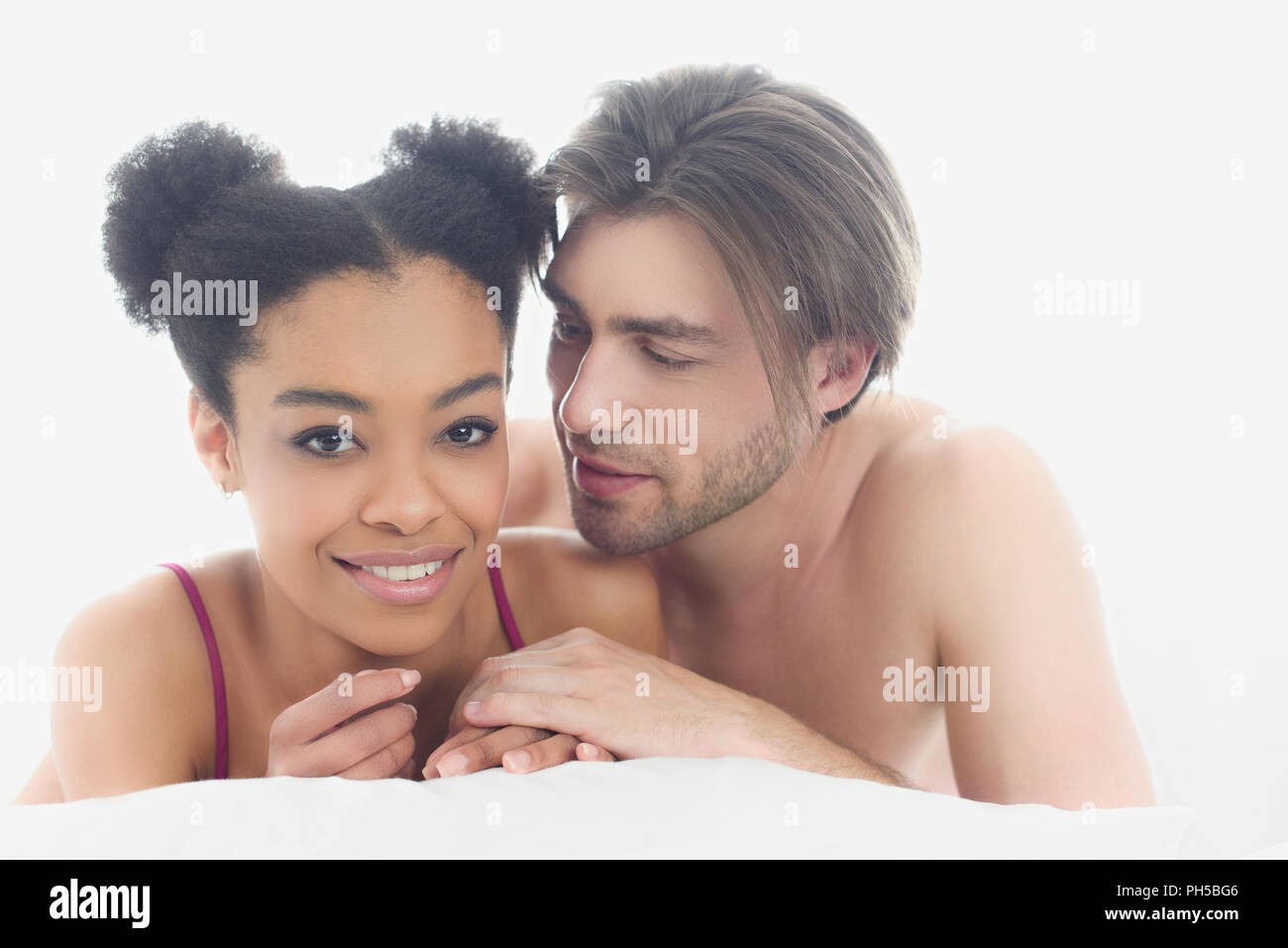 portrait of young interracial couple resting in bed together in morning at home Stock Photo