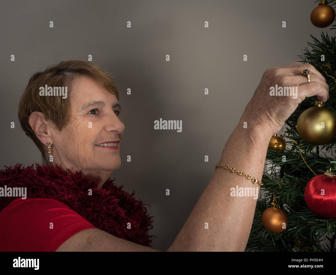 Horizontal portrait of an elderly woman decorating a Christmas tree Stock Photo