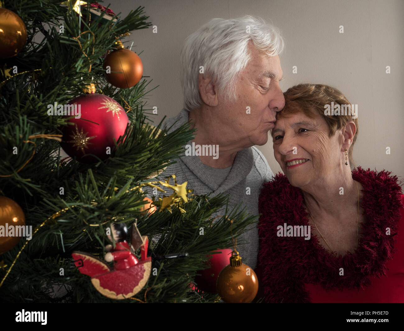 Closeup protrait of an elderly couple kissing by a Christmas tree Stock Photo