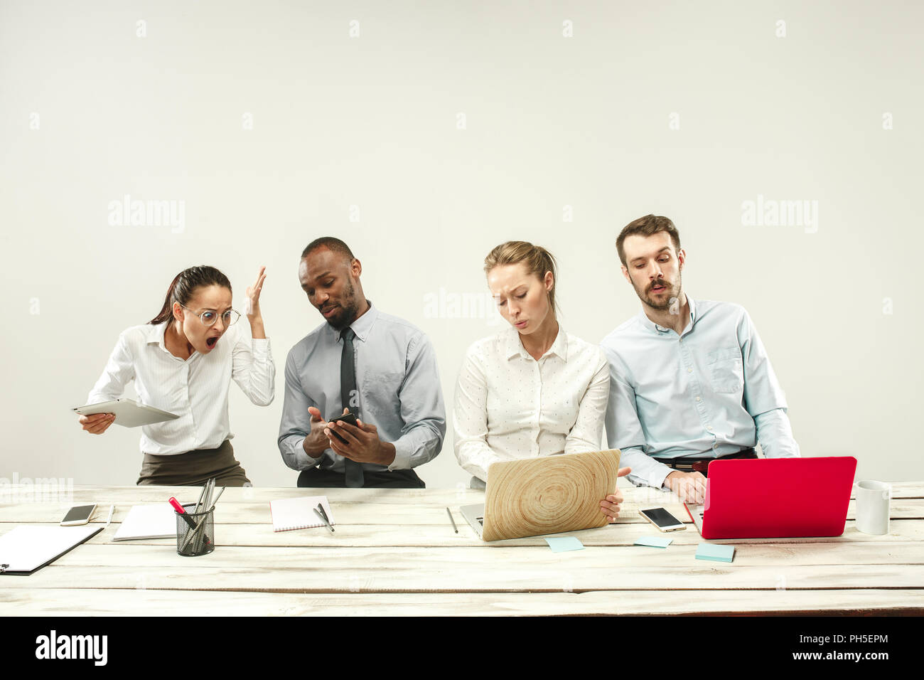 Young african and caucasian men and women sitting at office and working on laptops. The business, emotions, team, teamwork, workplace, leadership, meeting concept. different emotions of colleagues Stock Photo