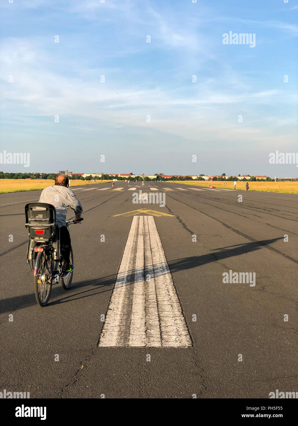 Cyclist riding his bike along the old runway at Tempelhofer Feld in Berlin, Germany in summer 2018. Stock Photo