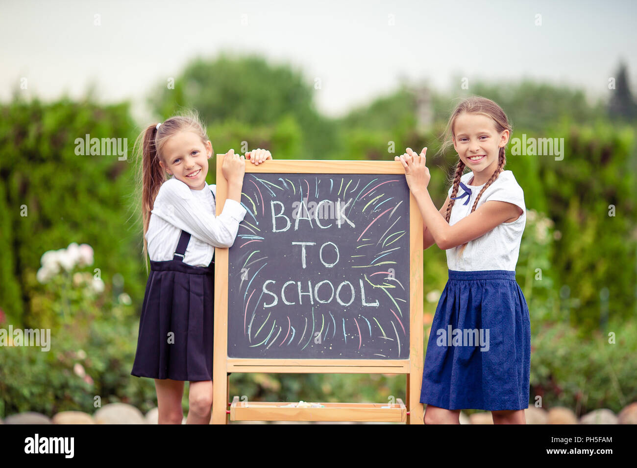 Happy little schoolgirls with a chalkboard outdoor Stock Photo - Alamy