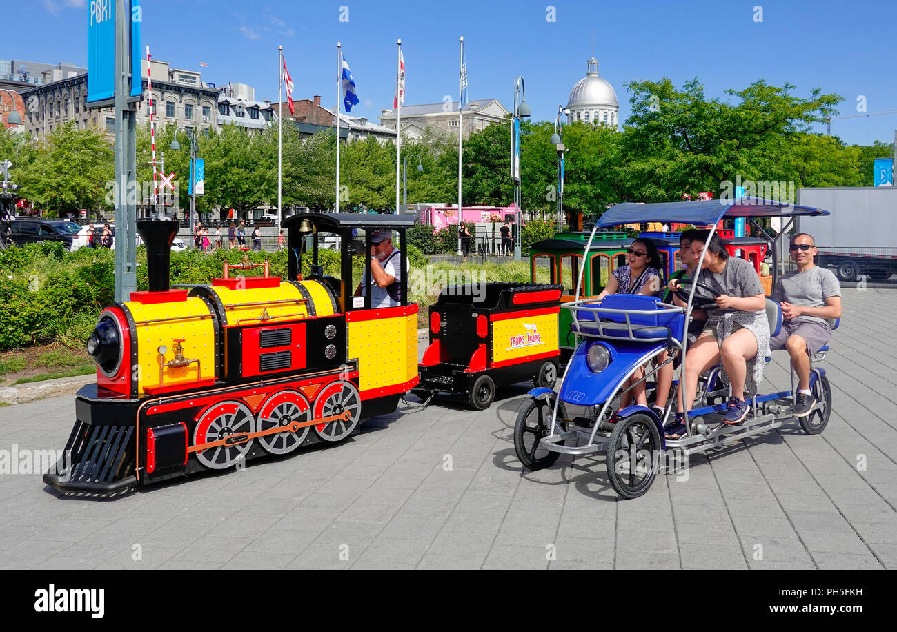 A children's toy steam engine train and Asian tourists racing near the Old Port in Montreal, QC, Canada Stock Photo