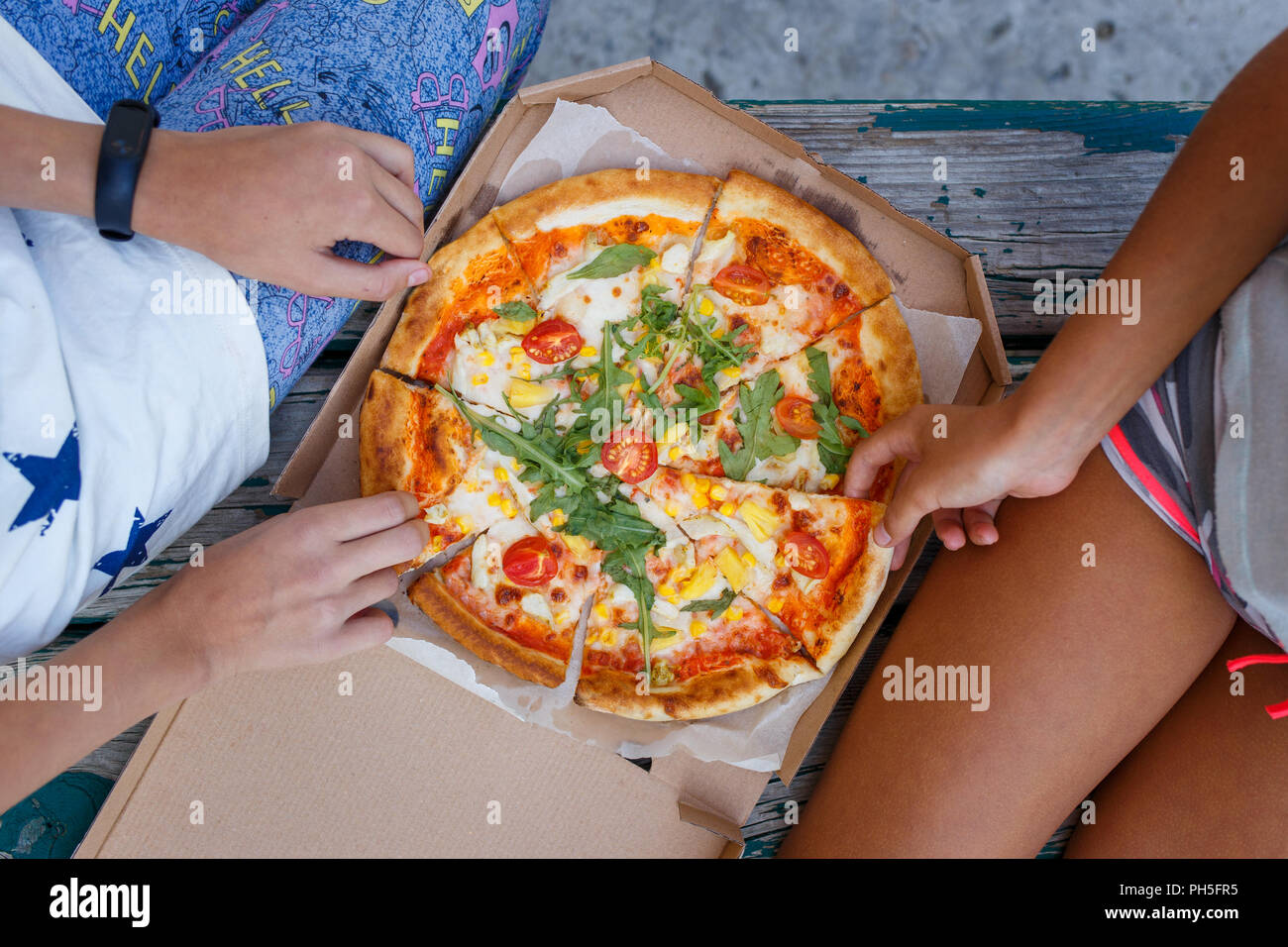Two girls eating pizza outdoors together. Top view image of summer picninc concept Stock Photo