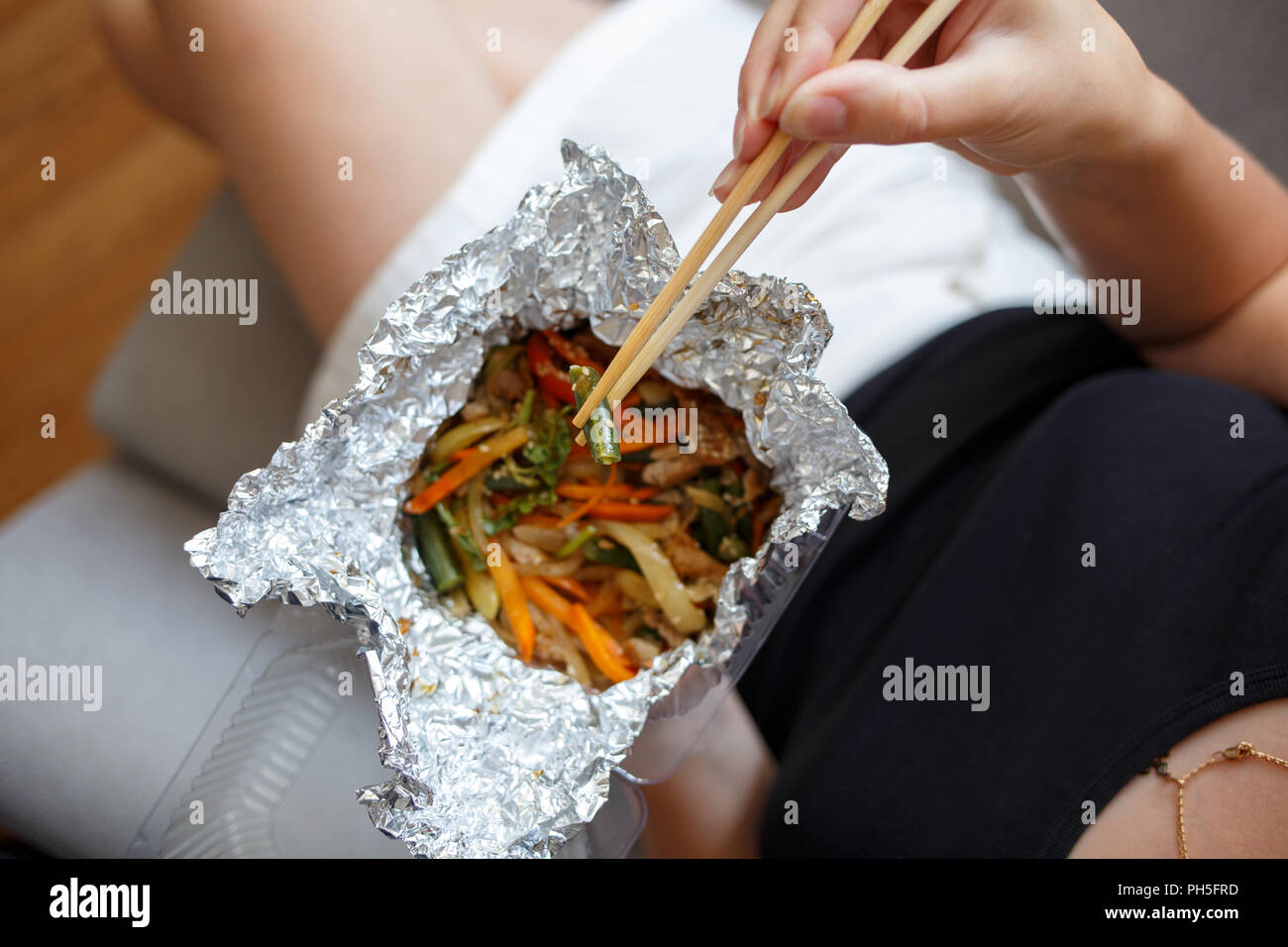 Young woman eating warm salad. Lunch time top view food delivey concept background Stock Photo