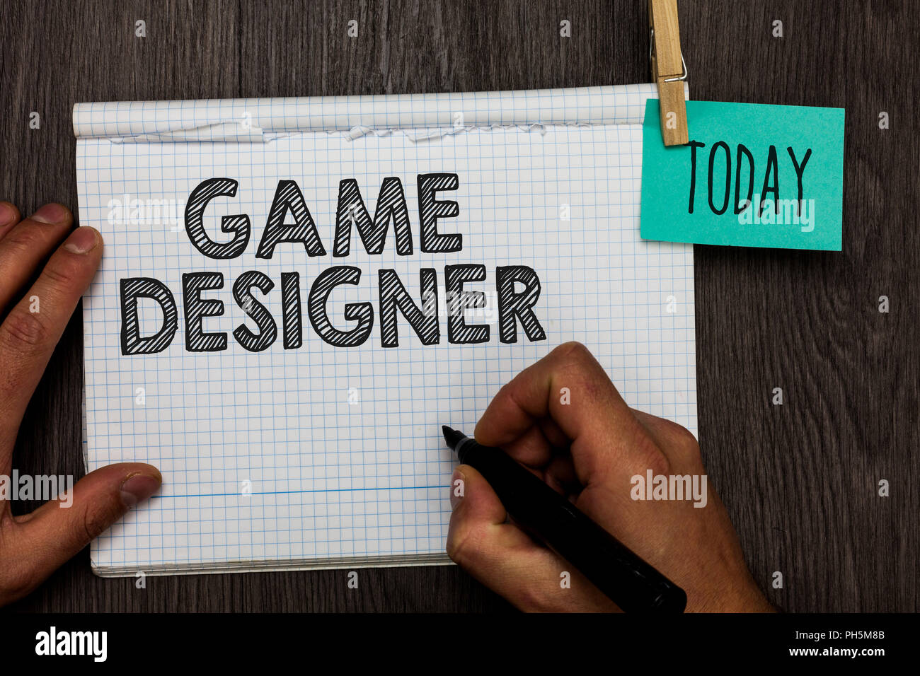 Handwriting text writing Game Designer. Concept meaning Campaigner Pixel Scripting Programmers Consoles 3D Graphics Open notebook clothespin holding r Stock Photo