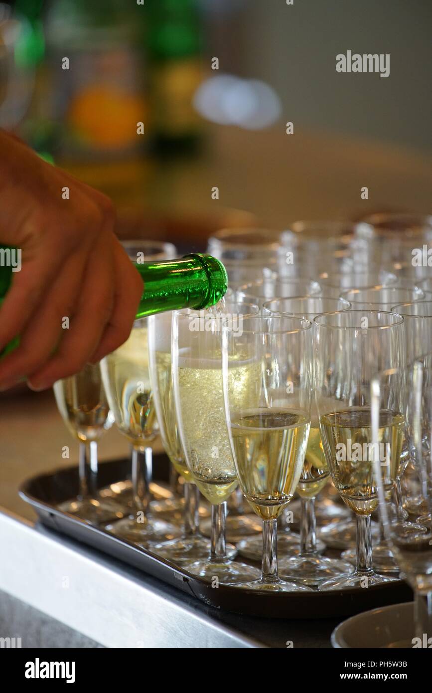 hand holding a bottle of sparkling wine, pouring in champagne cups