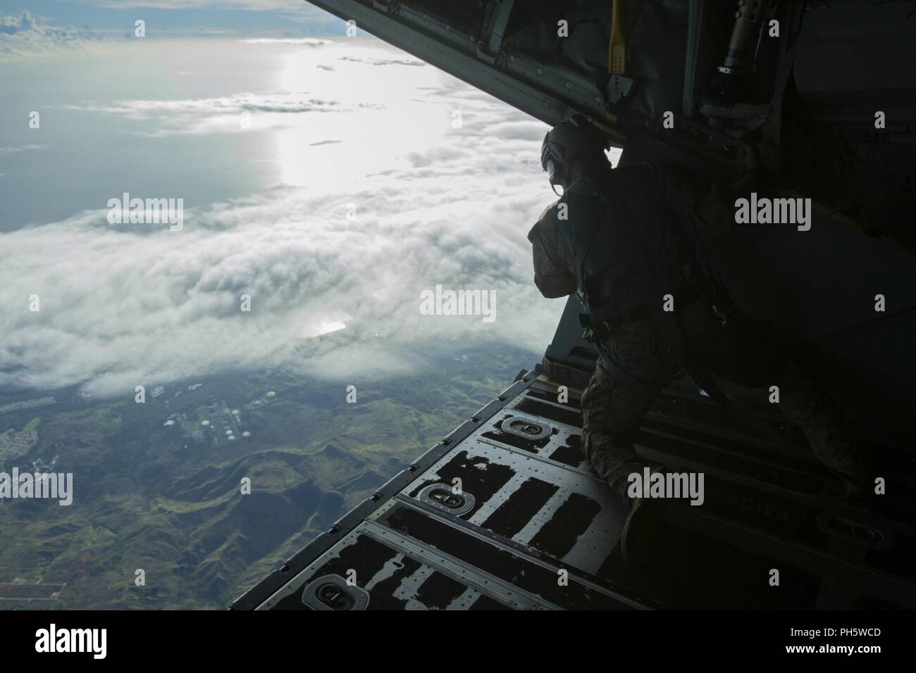 A reconnaissance Marine jump master with the 31st Marine Expeditionary Unit's Force Reconnaissance Platoon looks for the Designated Impact Point prior to instructing Marines to free fall during military free fall operations in flight, Guam, June 16, 2018. FRP trains for free fall operations using a high altitude low opening jump in order to hone insertion capabilities. The 31st MEU, the Marine Corps’ only continuously forward-deployed MEU, provides a flexible force ready to perform a wide-range of military operations. Stock Photo