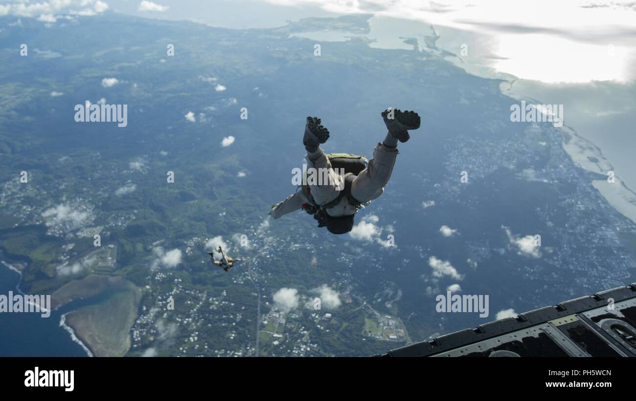 Reconnaissance Marines with the 31st Marine Expeditionary Unit’s Force Reconnaissance Platoon free fall off the ramp of a C-130 Hercules during military free fall operations in flight, Guam, June 16, 2018. FRP trains for free fall operations using a high altitude low opening jump in order to hone insertion capabilities. The 31st MEU, the Marine Corps’ only continuously forward-deployed MEU, provides a flexible force ready to perform a wide-range of military operations. Stock Photo