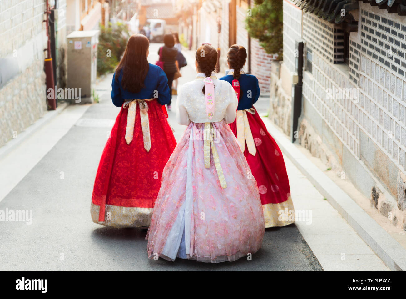 Back of three woman wearing hanbok walking through the traditional style houses of Bukchon Hanok Village in Seoul, South Korea. Stock Photo