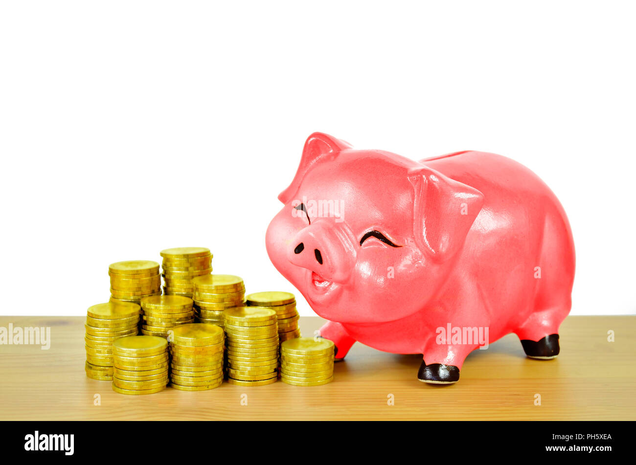 Pink piggy bank and gold coins on wood table isolated on white ...