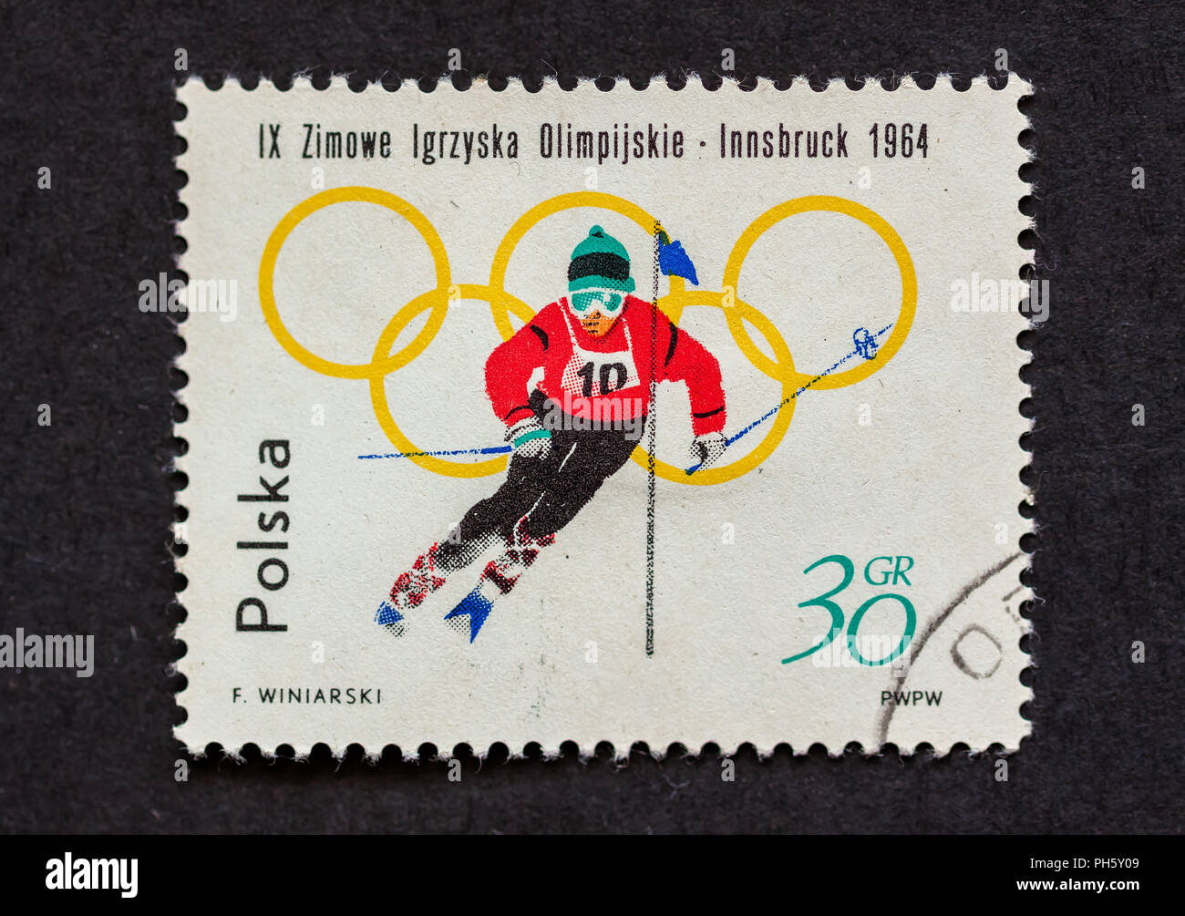A used postage stamp, in dark background, from Poland to commemorate 1964 Winter Olympic in Innsbruck, Austria. Stock Photo
