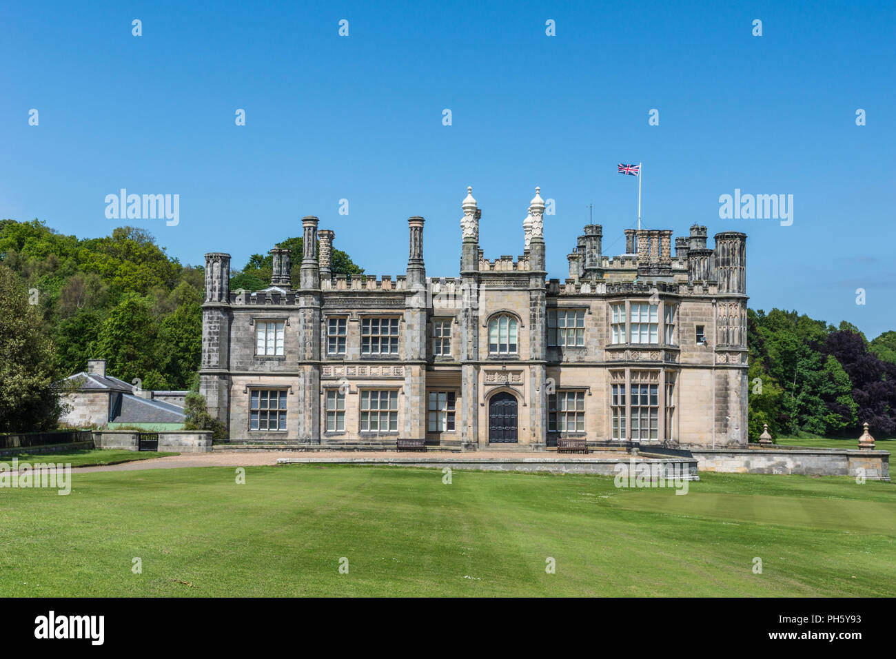 Edinburgh, Scotland, UK - June 14, 2012: Side facade of Dalmany house, mansion and castle in Tudor revival style on green lawn, with Brittish flag and Stock Photo