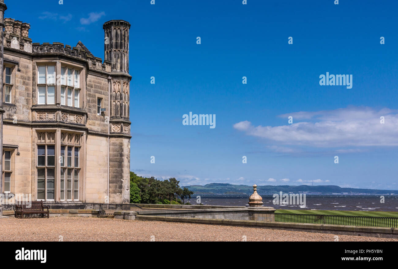 Edinburgh, Scotland, UK - June 14, 2012: Corner of Dalmany house, mansion and castle in Tudor revival style and Firth of Forth in back. Blue sky. Stock Photo