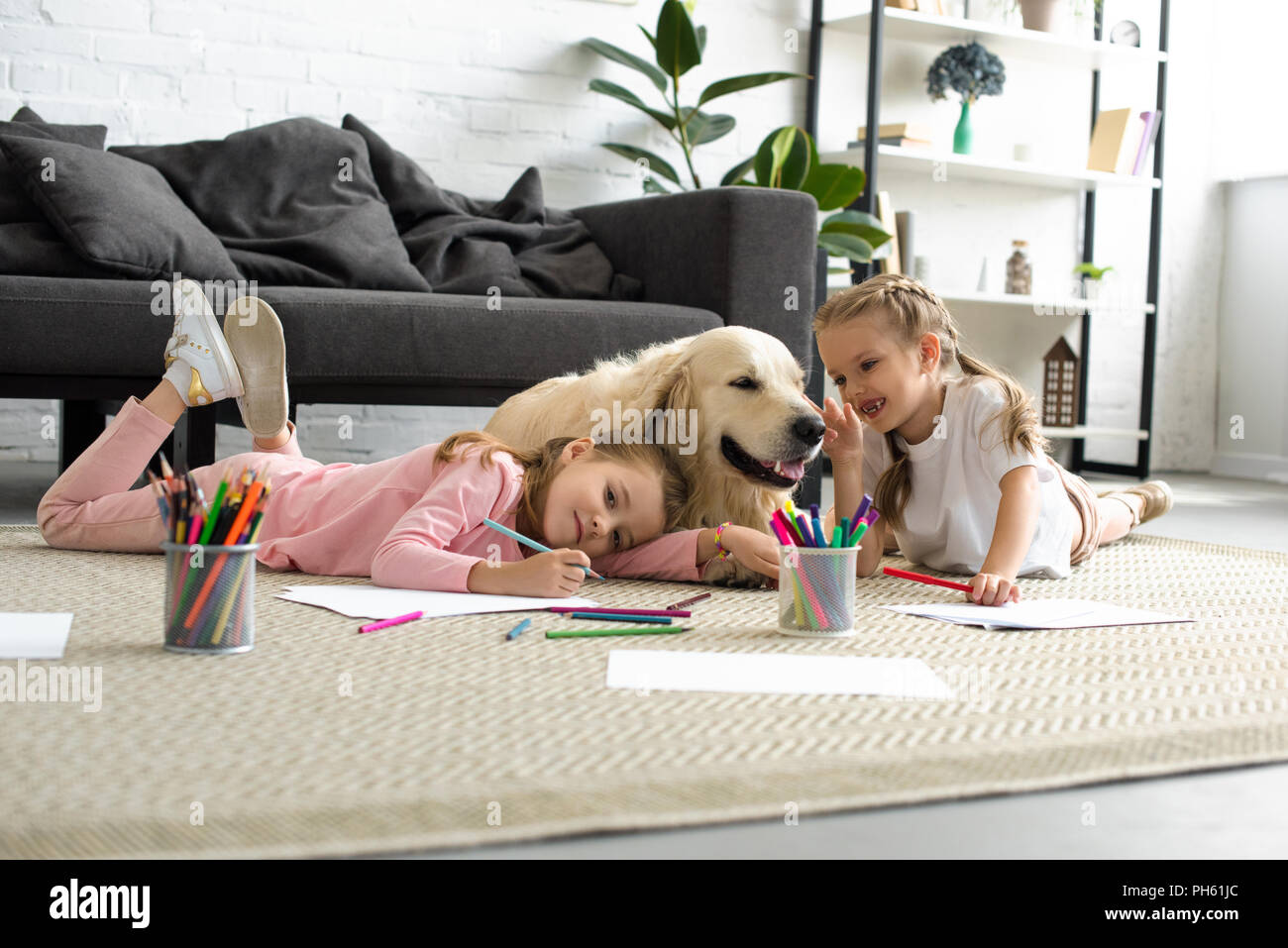 smiling kids lying on floor together with golden retriever dog at home Stock Photo