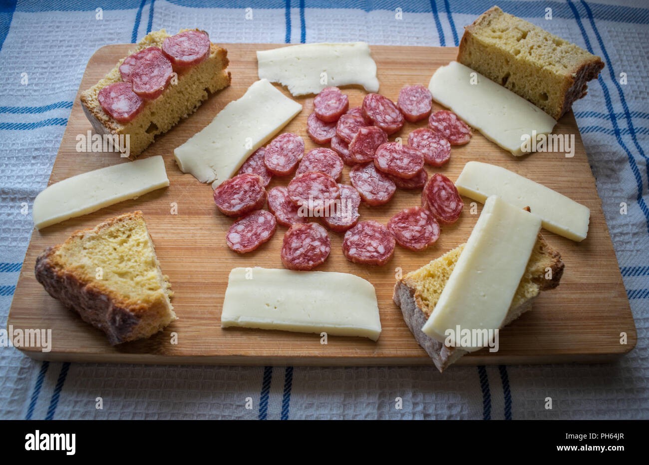 Cutting board with cheese, chorizo sausage and bread is a typical