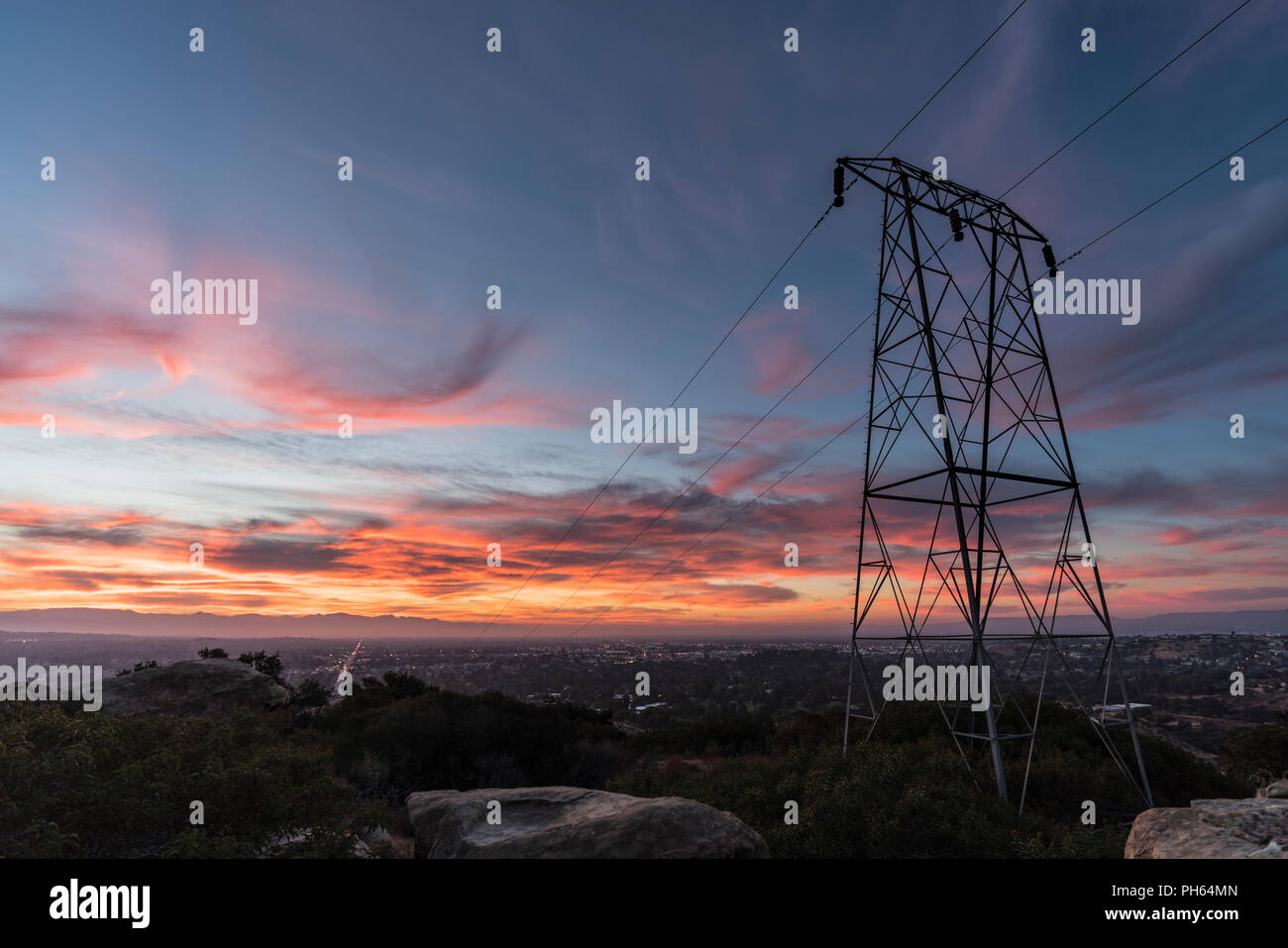 Sunrise view of electric power tower nestled in rocks above the western San Fernando Valley in Los Angeles, California. Stock Photo