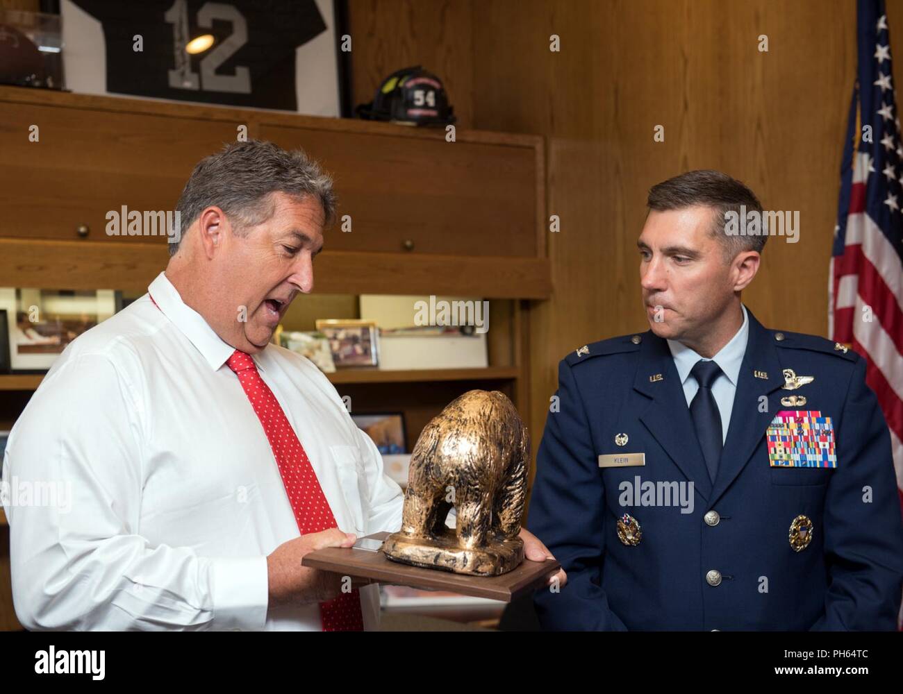 U.S. Air Force Col. John Klein, 60th Air Mobility Wing commander presents a Golden Bear to Assemblymember Jim Frazier, 11th District, during a presentation at the California State Capitol, Sacramento, June 25, 2018. Travis was honored by the California State Assembly with a Resolution honoring its 75th Anniversary. For the past 75 years, Travis AFB has been a focal point for the world as a power projection platform, a means to deliver hope, and a mission fueled by community support. Stock Photo