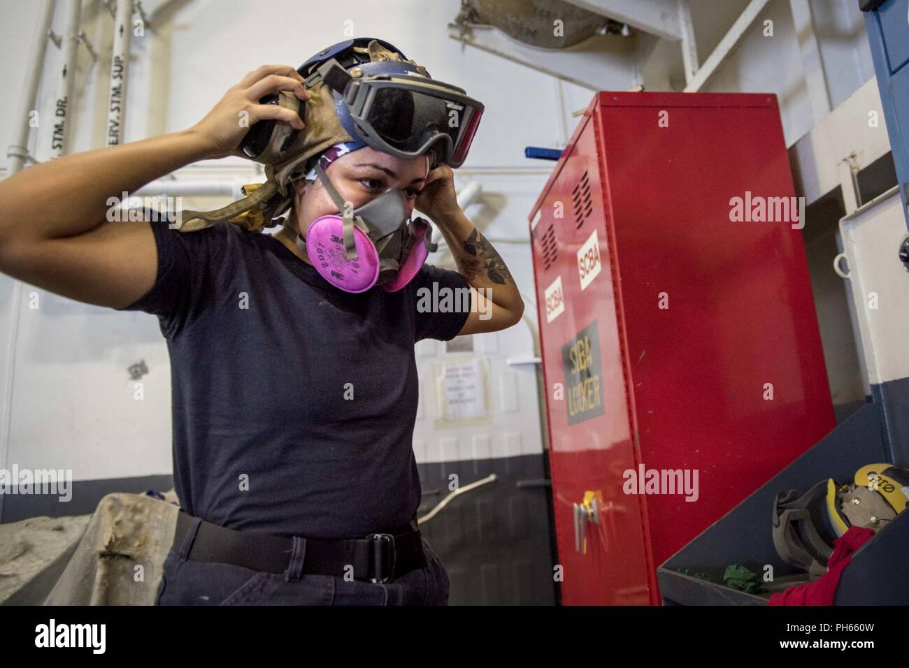 ATLANTIC OCEAN (June 26, 2018) Aviation Boatswain's Mate (Handling) Airman Shyla Souza, from Wahiawa, Hawaii, adjusts a cranial to be used for hearing and head protection before painting in the hangar bay aboard the aircraft carrier USS George H.W. Bush (CVN 77). The ship is underway conducting routine training exercises to maintain carrier readiness. Stock Photo