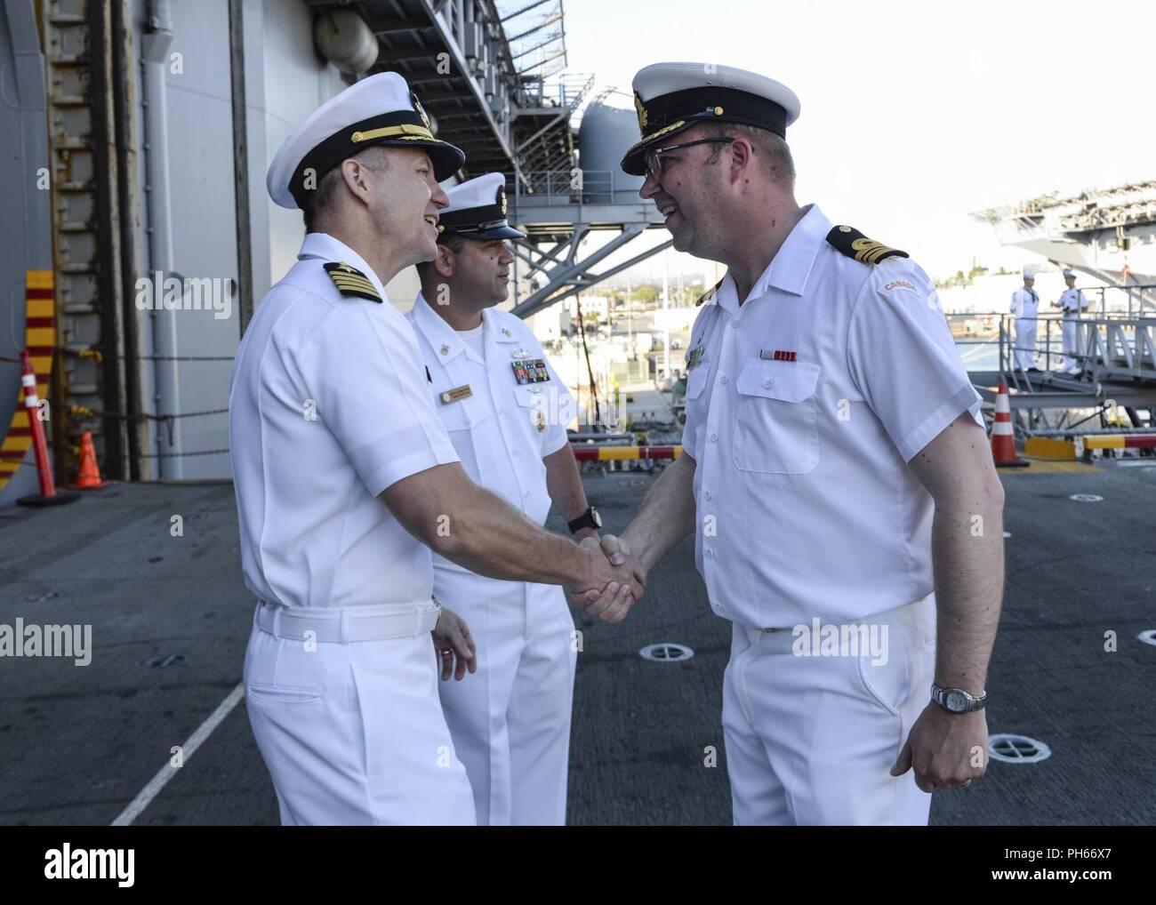 SAN DIEGO (June 27, 2018) Royal Canadian Navy Lt. Cmdr. Donald Thompson-Greiff is welcomed by Capt. Ronald A. Dowdell, executive officer of amphibious assault ship USS Boxer (LHD 4) for the Southern California portion of the Rim of the Pacific (RIMPAC SOCAL) opening reception June 27. Twenty-five nations, more than 45 ships and submarines, about 200 aircraft, and 25,000 personnel are participating in RIMPAC from June 27 to Aug. 2 in and around the Hawaiian Islands and Southern California. The world’s largest international maritime exercise, RIMPAC provides a unique training opportunity while f Stock Photo