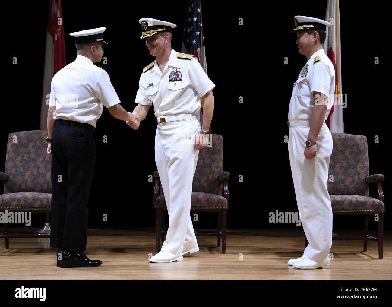 MANAMA, Bahrain (June 28, 2018) Vice Adm. Scott Stearney, middle, commander of U.S. Naval Forces Central Command, U.S. 5th Fleet and Combined Maritime Forces,  shakes the hand of Republic of Singapore Navy Rear Adm. Saw Shi Tat, oncoming commander of Combined Task Force (CTF) 151, left, during the task force's change of command ceremony on Naval Support Activity Bahrain. CTF 151's mission is to disrupt piracy at sea and to engage with regional and other partners to build capacity and improve relevant capabilities in order to protect global maritime commerce and secure freedom of navigation. Stock Photo