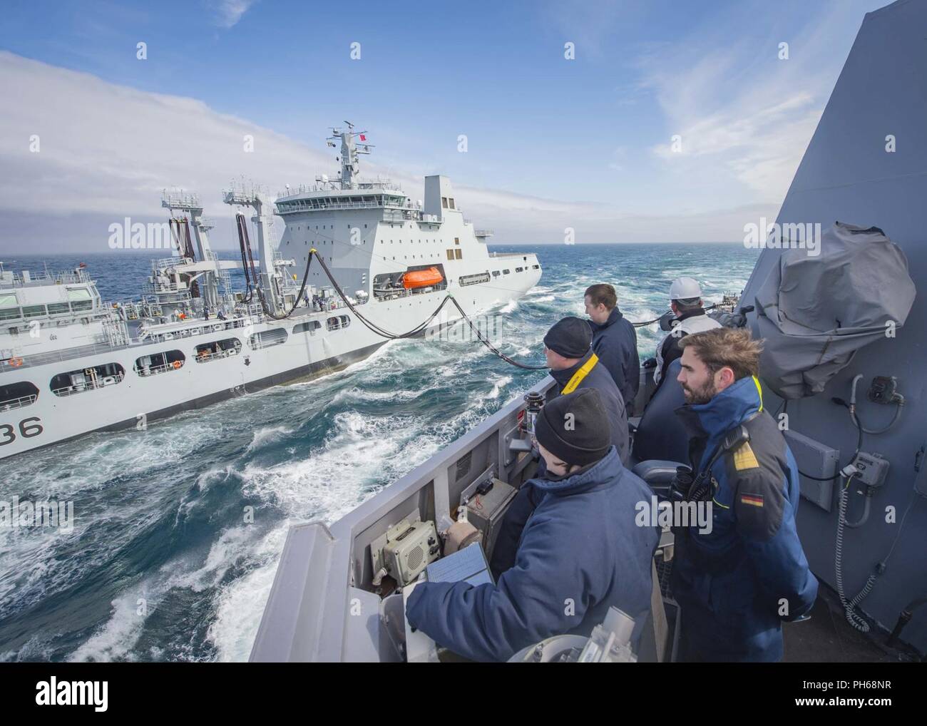 NORWEGIAN SEA (June 26, 2018) Sailors aboard the guided-missile destroyer USS Farragut (DDG 99) observe fuel being transferred to the ship during an underway replenishment with the British Royal Fleet Auxiliary replenishment tanker RFA Tidespring (A136). Farragut is currently deployed as part of the Harry S. Truman Carrier Strike Group. With USS Harry S. Truman (CVN 75) as the flagship, deployed strike group units include staffs, ships and aircraft of Carrier Strike Group Eight (CSG 8), Destroyer Squadron Two Eight (DESRON 28) and Carrier Air Wing One (CVW-1); as well as Sachsen-class German F Stock Photo