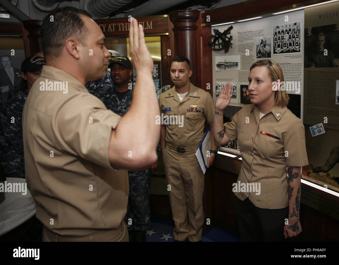 NORFOLK, Va. (June 29, 2018) Aviation Boatswain’s Mate (Fuel) 3rd Class Autumn Landrum, from Oak Ridge, Tennessee, assigned to USS Gerald R. Ford’s (CVN 78) air department, recites the oath of enlistment given by Chief Aviation Boatswain’s Mate (Fuel) Jorge Ramos during her reenlistment ceremony in the ship’s tribute room. Stock Photo