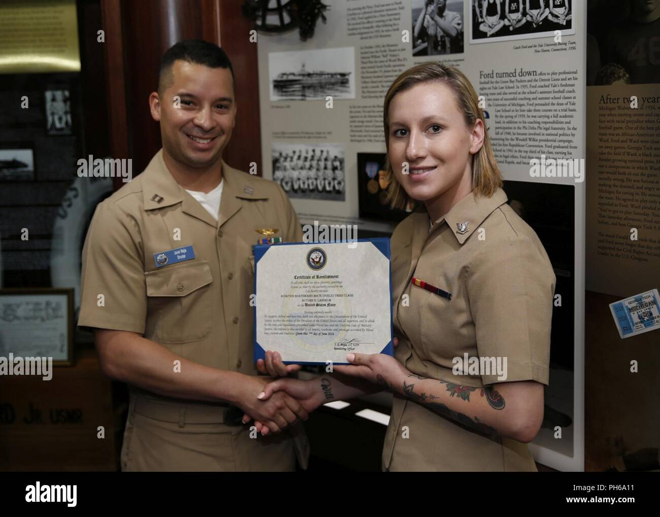NORFOLK, Va. (June 29, 2018) Aviation Boatswain’s Mate (Fuel) 3rd Class Autumn Landrum, from Oak Ridge, Tennessee, assigned to USS Gerald R. Ford’s (CVN 78) air department, receives a certificate of reenlistment from Lt. Javier Mejia during her reenlistment ceremony in the ship’s tribute room. Stock Photo