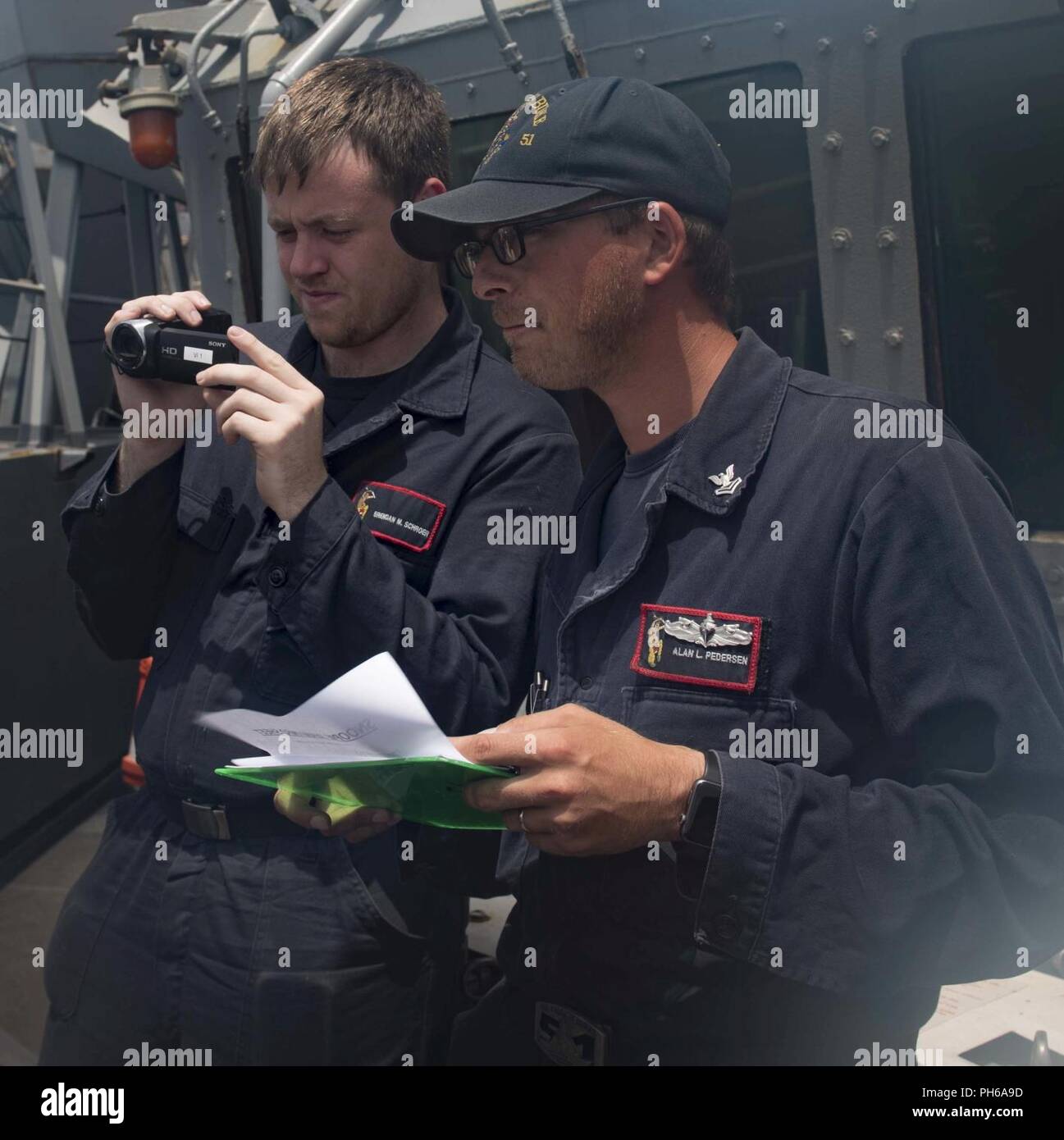 U.S. 5TH FLEET AREA OF OPERATIONS (June 28, 2018) Yeoman Seaman Brendan Schroer, left, and Personnel Specialist 2nd Class Alan Pederson record a simulated contact as part of a ship's nautical or otherwise photographic investigation and examination team exercise aboard the guided-missile destroyer USS Arleigh Burke (DDG 51). Arleigh Burke is currently deployed as part of the Harry S. Truman Carrier Strike Group. With the aircraft carrier USS Harry S. Truman (CVN 75) as the flagship, deployed strike group units include staffs, ships, and aircraft of Carrier Strike Group Eight (CSG 8), Destroyer  Stock Photo